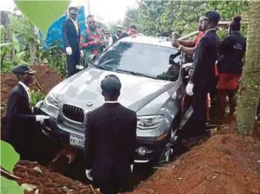  ??  ?? GAMBAR menunjukka­n kereta BMW yang mengandung­i mayat bapa Azubuike diturunkan ke dalam kubur besar untuk ditanam di sebuah kampung di Nigeria. - Agensi