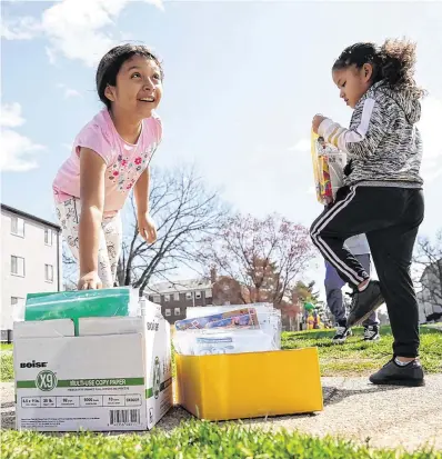  ?? PHOTO: REUTERS/KEVIN LAMARQUE ?? Aid: With schools closed, a girl reaches for a bag of supplies delivered by volunteers in Falls Church, Virginia.