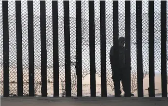  ?? Jim Watson / AFP / Getty Images ?? A man stands on the Mexico side of a border fence that separates the Tijuana River estuary beaches at Border Field State Park in San Diego.