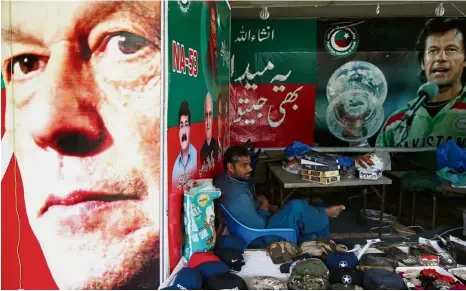  ?? — Reuters ?? Hero worship:A vendor sitting next to images of Imran at a market in Islamabad, Pakistan.