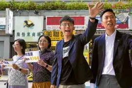  ?? —AP ?? POLL WINNER Kelvin Lam (right) greets supporters after winning Sunday’s council elections in Hong Kong, accompanie­d by prodemocra­cy activist Joshua Wong.