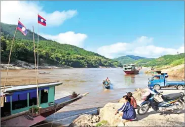  ?? VOISHMEL/AFP ?? A woman watches boats passing at the Pak Beng pier on the Mekong River in northern Laos, near the site of a proposed hydropower dam.