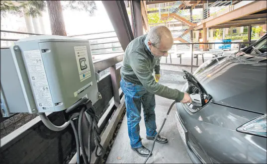  ?? Tribune News Service ?? A man charges his Nissan Leaf electric car in a public garage in Palo Alto, Calif.