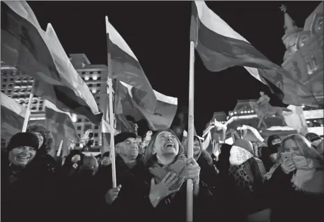  ?? PAVEL GOLOVKIN/AP PHOTO ?? People wave Russian flags as they wait for election results in Manezhnaya square, near the Kremlin, in Moscow on Sunday. Russians are voting in a presidenti­al election in which Vladimir Putin is seeking a fourth term.