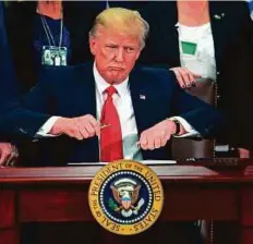  ??  ?? US President Donald Trump takes the cap off a pen to sign an executive order to start the Mexico border wall project.