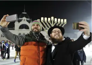  ?? (Courtesy EMIH) ?? RABBI SLOMO KOVES, right, and a participan­t at Chabad Hungary’s 2015 Hanukkah on Ice event take selfies at Budapest’s City Park Ice Rink in 2015.