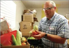  ?? FILE PHOTO ?? Jim Lewis packs a box for clients at GRACE Place in Lincoln that includes homegrown vegetables from Lincoln’s new community garden.