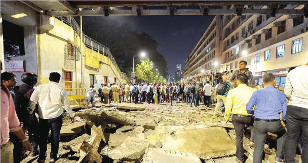  ?? — AFP photo ?? Onlookers and office goers gather around rubbles of a footbridge outside the Chattrapat­i Shivaji Maharaj Terminus railway complex in Mumbai.