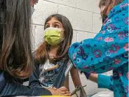  ?? Shawn Rocco / Associated Press ?? Alejandra Gerardo, 9, looks at her mom, Susanna Naggie, as she gets a shot during a clinical trial.