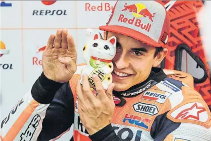  ?? FOTO: GETTY ?? Marc Márquez y su Gato de la Suerte Cada año los de Shoei se responsabi­lizan de que esté la figurita en una repisa de su box en Motegi