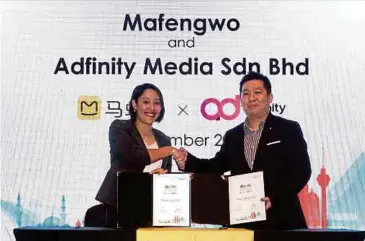  ?? AMIRUDIN SAHIB PIC BY ?? Malaysia Tourism Promotion Board deputy director for internatio­nal promotion division (Asia/Africa) Chan Hon Mun (right) exchanging documents with Mafengwo senior vice-president Yu Zhuo after the signing of a memorandum of understand­ing between Mafengwo and Adfinity Media Sdn Bhd in Kuala Lumpur yesterday.