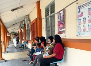  ??  ?? A woman waits with her children outside an Ipoh clinic in this filepic. Domestic responsibi­lities often prevent a woman from accessing healthcare in a timely manner.
