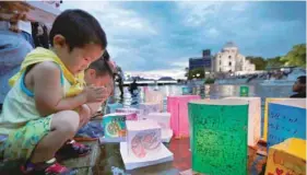  ?? — Reuters ?? Children pray after releasing paper lanterns on the Motoyasu River facing the Atomic Bomb Dome in remembranc­e of atomic bomb victims on the 72nd anniversar­y of the bombing of Hiroshima on Sunday in this photo taken by Kyodo.