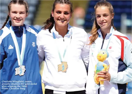  ??  ?? Charlotte Wingfield, centre, proudly displays the gold medal after winning the 200m Photo: Christine Borg