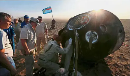  ??  ?? Welcome wagon: A search and rescue team opening the hatch of the Soyuz capsule carrying the ISS crew after its landing near Dzhezkazga­n. — Reuters