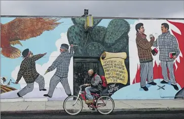  ?? Luis Sinco Los Angeles Times ?? A BICYCLIST rides past a gang mural in Wilmington. An investigat­ion into the link between the Westside and Eastside Wilmas and imprisoned Mexican Mafia members led to seven arrests on drug and gun charges.