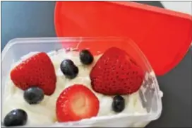  ??  ?? Greek yogurt with strawberri­es and blueberrie­s are displayed. it’s important to include fruit in a packed school lunch.