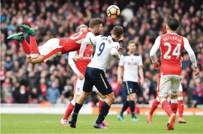  ?? — AFP ?? LONDON: Arsenal’s German defender Shkodran Mustafi (L) dives through the air as he vies with Tottenham Hotspur’s Dutch striker Vincent Janssen during the English Premier League football match between Arsenal and Tottenham Hotspur at the Emirates...