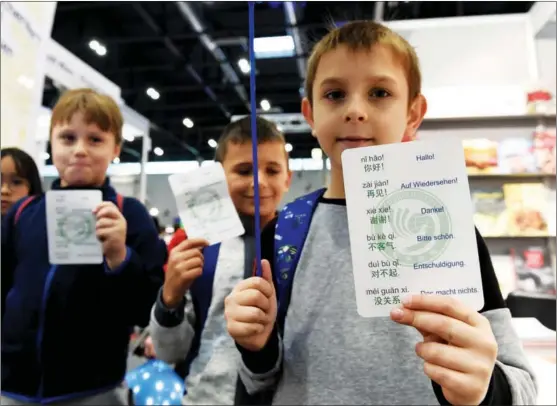  ?? GUO CHEN / XINHUA ?? Children display Chinese learning cards in front of an exhibition booth of the Confucius Institute at the University of Vienna during the Vienna Internatio­nal Book Fair in November 2021.