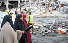  ?? Associated Press ?? Somali women stand Sunday at the scene of Saturday’s blast in Mogadishu, Somalia. The powerful bomb blast in Somalia’s capital was the deadliest single attack ever in the Horn of Africa nation, police and hospital sources said.