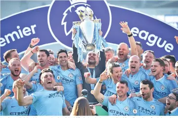  ?? - AFP photo ?? Manchester City’s Spanish manager Pep Guardiola (C) lifts the Premier League trophy with staff members after their 4-1 victory in the English Premier League football match between Brighton and Hove Albion and Manchester City at the American Express Community Stadium in Brighton, southern England.