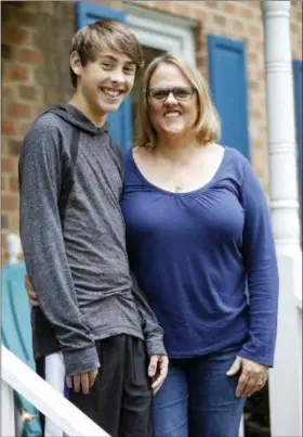  ?? STEVE HELBER — THE ASSOCIATED PRESS ?? Jodi Smith Lemacks and her son, Joshua, pose for a photo in front of their home in Richmond, Va., Tuesday. Lemacks is nervous about changing or losing her job because that could mean cutting off her son Joshua from heart specialist­s he’s seen his entire life.