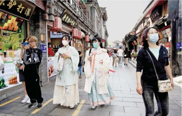  ?? Agence France-presse ?? ↑ People walk through a shopping alley near Houhai lake in Beijing, China, on Sunday.