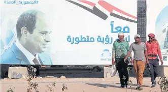  ?? ?? Workers pass a billboard featuring President el-Sisi in Egypt’s New Capital