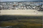  ?? ?? Workers in protective suits clean the contaminat­ed beach after an oil spill in Newport Beach.