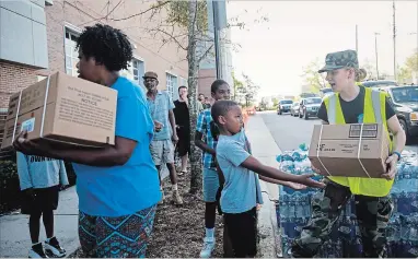  ?? ERIC THAYER NEW YORK TIMES ?? People leave a food and water distributi­on centre in downtown Wilmington, N.C. in the aftermath of Hurricane Florence, Tuesday. Even as the remnants of Florence pulled away, it was clear that the turmoil had only begun; Wilmington, one of North Carolina’s largest cities, was virtually cut off by floodwater­s.