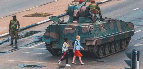  ?? WAR AND PEACE: Young women walk past a tank in Harare as the military takes over the country. Picture: AFP PHOTO ??