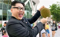  ?? — AFP ?? A Kim Jong Un impersonat­or poses holding a durian fruit in front of the Esplanade theatre in Singapore on Sunday.