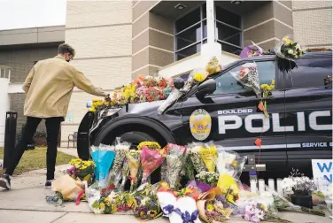  ?? David Zalubowski / Associated Press ?? A man leaves flowers on a police cruiser. An officer was one of the victims of the Boulder shooting.