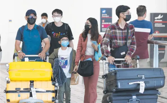  ?? Picture: STEVE POHLNER ?? HARD HIT: People wear masks at the Brisbane Internatio­nal Airport yesterday. The travel industry has been hard hit by the coronaviru­s scare.