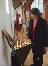  ?? GARY NYLANDER/The Daily Courier ?? Susan Sanger lights a memorial candle.