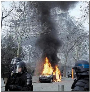  ?? AP/KAMIL ZIHNIOGLU ?? Riot police respond Saturday at the Eiffel Tower in Paris near an anti-terror-squad vehicle that was set on fire by yellow vest protesters. One demonstrat­or’s hand was ripped apart as a group tried to storm the French National Assembly before moving toward the Eiffel Tower.