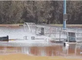  ??  ?? Tom Horan hoses off tennis courts at KDV Sport at Carrara yesterday and (right) Magic United football club faced a huge clean-up once floodwater­s subsided. Pictures: MIKE BATTERHAM