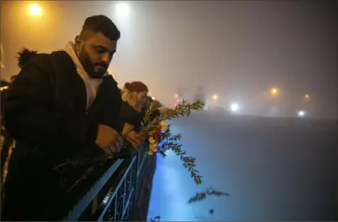  ?? Metin Yoksu/Associated Press photos ?? People toss carnations into the Orontes River on Tuesday as they mark the one-year anniversar­y of the country's catastroph­ic earthquake, in the city of Antakya, southern Turkey.