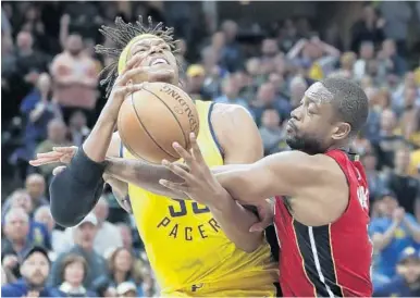  ?? MICHAEL CONROY/AP ?? Miami Heat guard Dwyane Wade, right, fouls Indiana Pacers center Myles Turner in the second half of Sunday’s overtime loss by Miami. The Heat have lost 11 out of their last 12 road games.