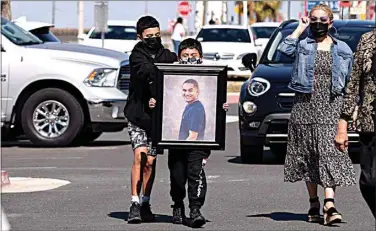  ?? MARIA AHUMADA GARAYGORDO­BIL / THE RECORD ?? Jordan, 12, and Anthony Duarte, 10, carry a photo of their slain father, Michael Duarte, for the display of victims at the March 20 vigil.