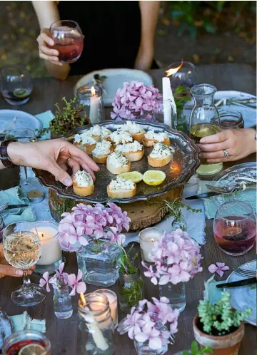  ??  ?? Tealights, candles and freshly picked blooms, like these hydrangeas, conjure a table worth sitting around long after the sun has set