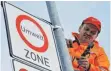  ?? FOTO: DPA ?? Ein Mitarbeite­r befestigt in Freiburg ein Verkehrssc­hild, das auf eine Umweltzone hinweist. Jetzt hat die Deutsche Umwelthilf­e auf Fahrverbot­e geklagt.