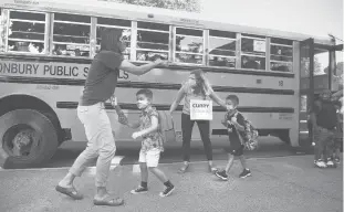  ?? COURANT FILE PHOTO ?? Teachers Jen Barton, left, and Andrea Curry help students Leo Flanagan, left, Dominic Claudio, center, and Antoine Reddick, far right, off the bus outside Naubuc Elementary School in Glastonbur­y on Aug.26.