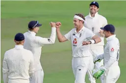  ??  ?? England’s Stuart Broad (centre) celebrates with teammates after dismissing West Indian batsman John Campbell during the third day of their third Test at Old Trafford in Manchester, England, on Sunday.
— AP