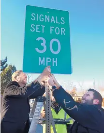  ?? GREG SORBER/JOURNAL ?? Albuquerqu­e Mayor Tim Keller, left, and City Councilor Pat Davis install a signal timing sign on Lead at Tulane as a traffic control measure.