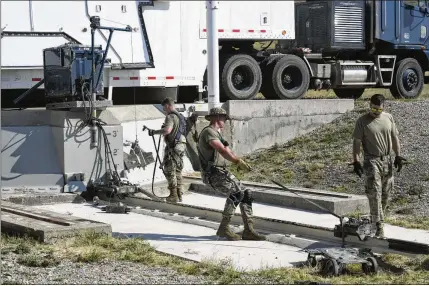  ?? JOHN TURNER/U.S. AIR FORCE ?? Airman 1st Class Jonathan Marrs, 21, (left) and Senior Airman Jacob Deas, 23, work to dislodge the 110-ton cement and steel blast door covering the top of the Bravo-9 nuclear missile silo at Malmstrom Air Force Base in Montana. When the first 225-pound aluminum tow, or “mule,” could not pull the door open, Marrs dragged down a second tow to give them more power.