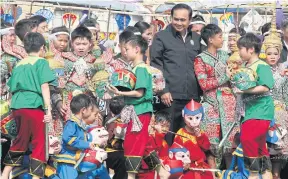  ??  ?? PREMIER PASSIONS: Prime Minister Prayut Chan-o-cha is surrounded by children in costumes who put on performanc­es on Children’s Day at Government House yesterday.