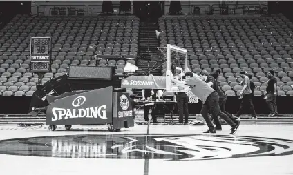  ?? Ashley Landis / Associated Press ?? Crews remove a basketball hoop after Dallas defeated Denver last week. It’s unclear when the NBA will play games again.