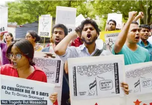  ?? AFP ?? Activists and students hold placards as they shout slogans during a protest rally against the recent death of 64 children at a government hospital in northern India, in New Delhi on Sunday. —