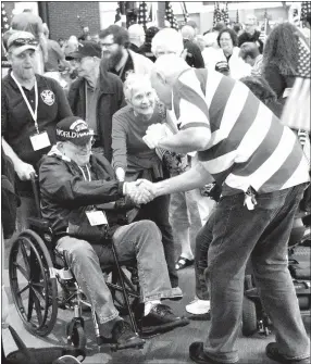  ?? Photo by Mike Eckels ?? A World War II veteran received a handshake from a well-wisher during the 2017 O&A Honor Flight welcome-home ceremony April 19 at Northwest Arkansas Regional Airport in Highfill.